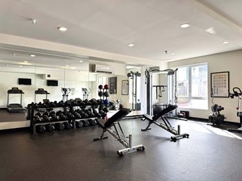 A gym with a variety of equipment including weights and cardio machines.
